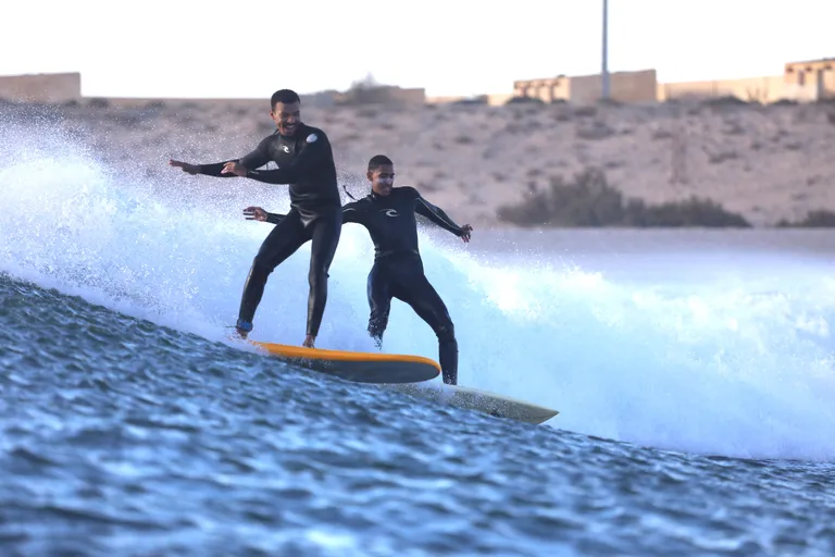 Coach de surf aidant un surfeur à Dakhla